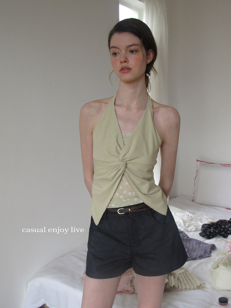 Model wearing a light beige halter top with black shorts in a casual indoor outfit