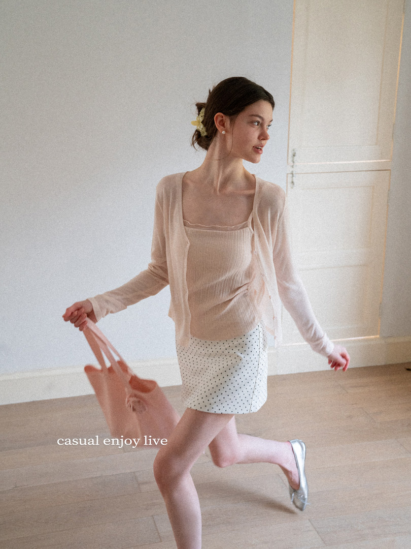 Woman wearing a light beige cardigan and tank top with a polka dot mini skirt