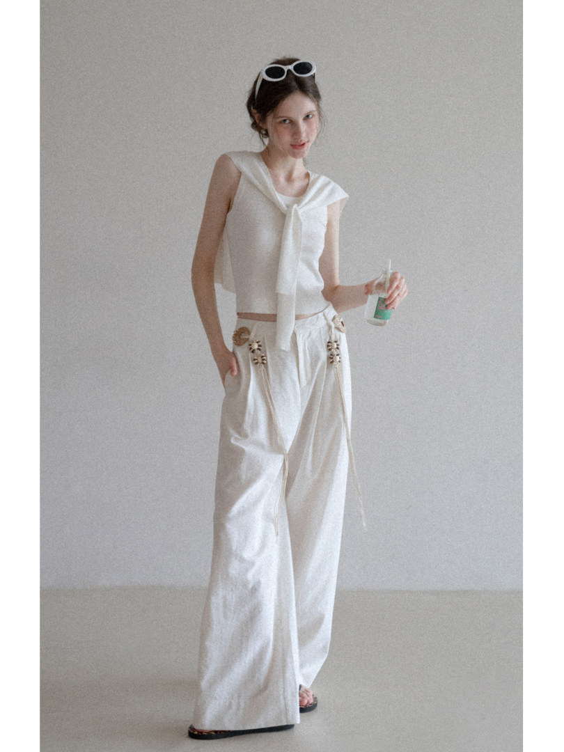 Model wearing a white sleeveless top and wide-leg pants