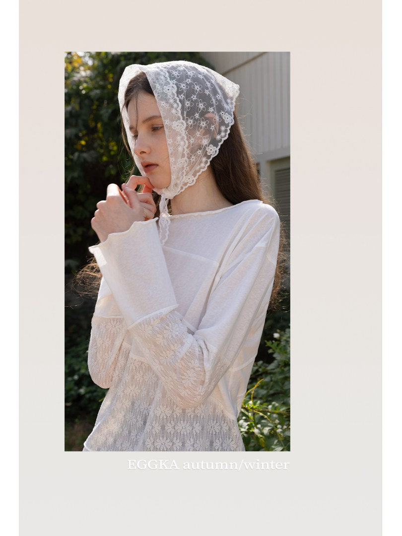 Model wearing a white lace-trim long-sleeve top and lace bonnet outdoors