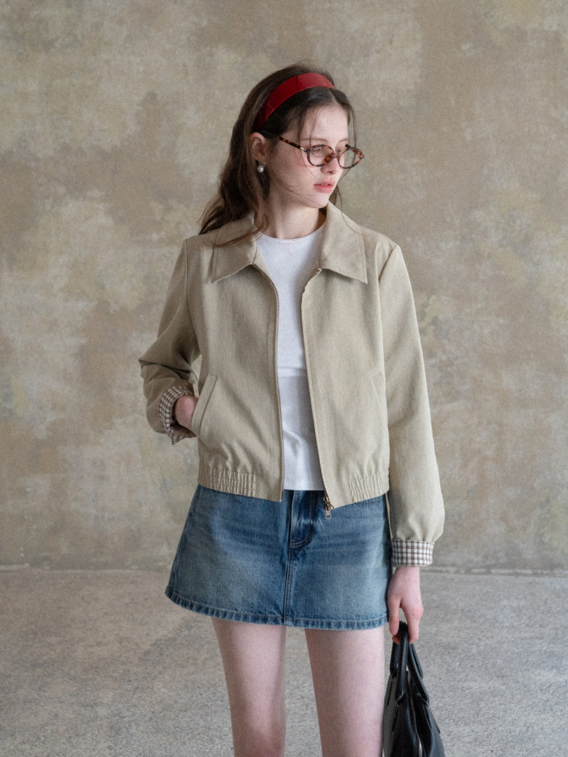 Woman wearing a beige lightweight jacket with a denim skirt