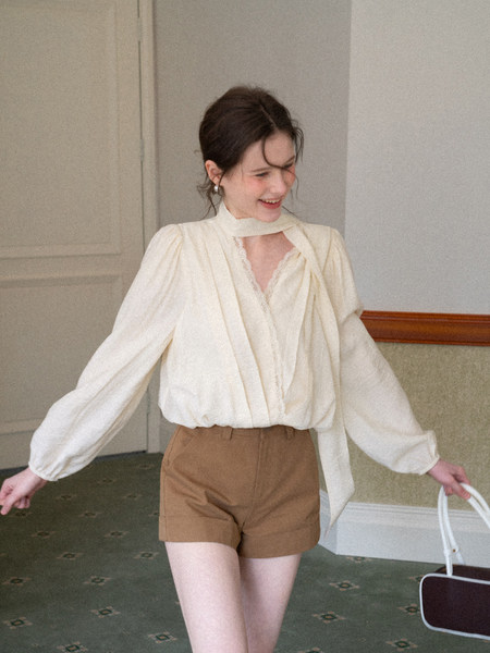 Woman wearing an ivory blouse with brown shorts