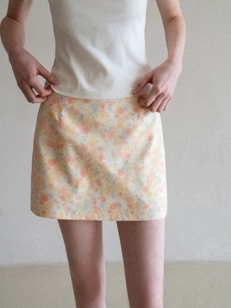 Model wearing a pastel floral mini skirt with a cream top