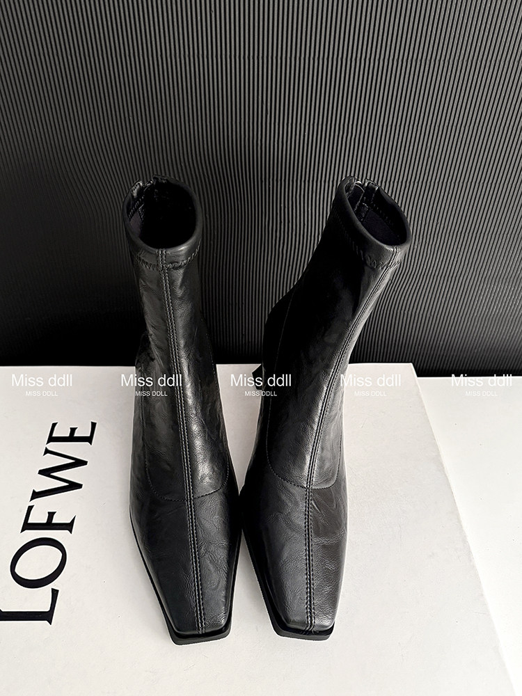 Black leather ankle boots displayed on a white surface