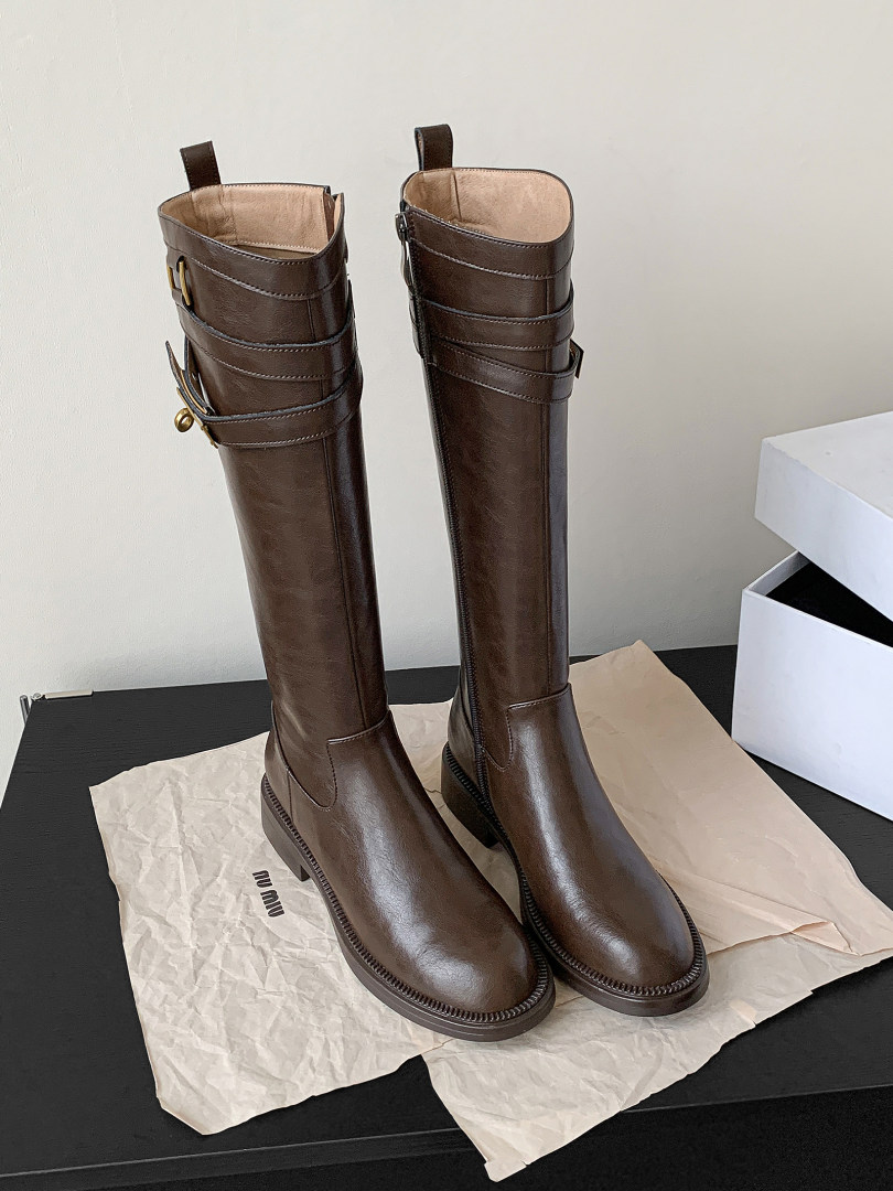 Pair of tall brown leather knee-high boots displayed on paper