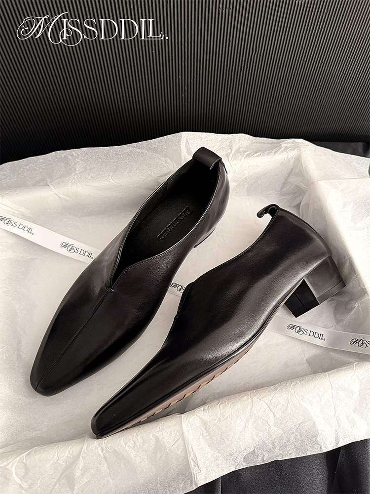 Black pointed-toe low-heel slip-on shoes on tissue paper