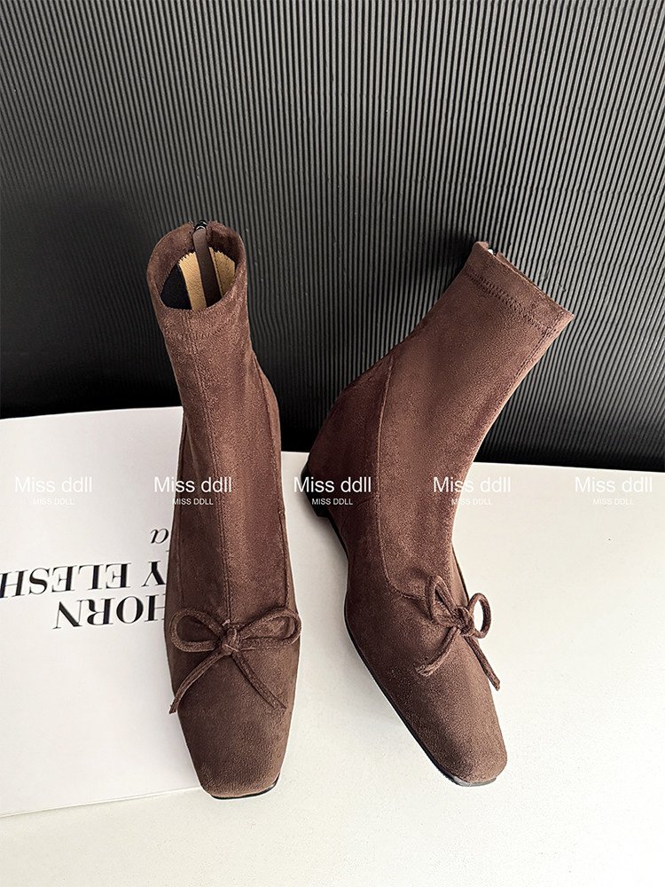 Pair of brown ankle boots with bow detail on a white background