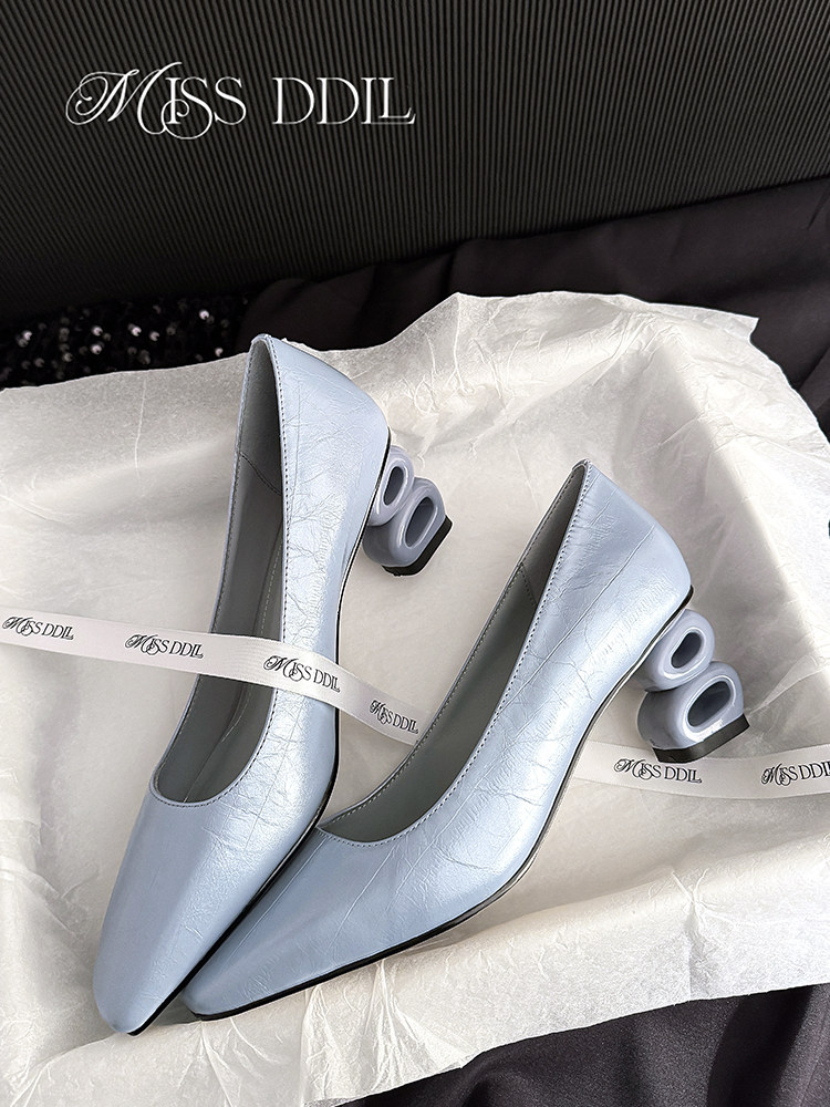 Pair of light blue high-heeled pumps with sculptural heel detail on tissue paper
