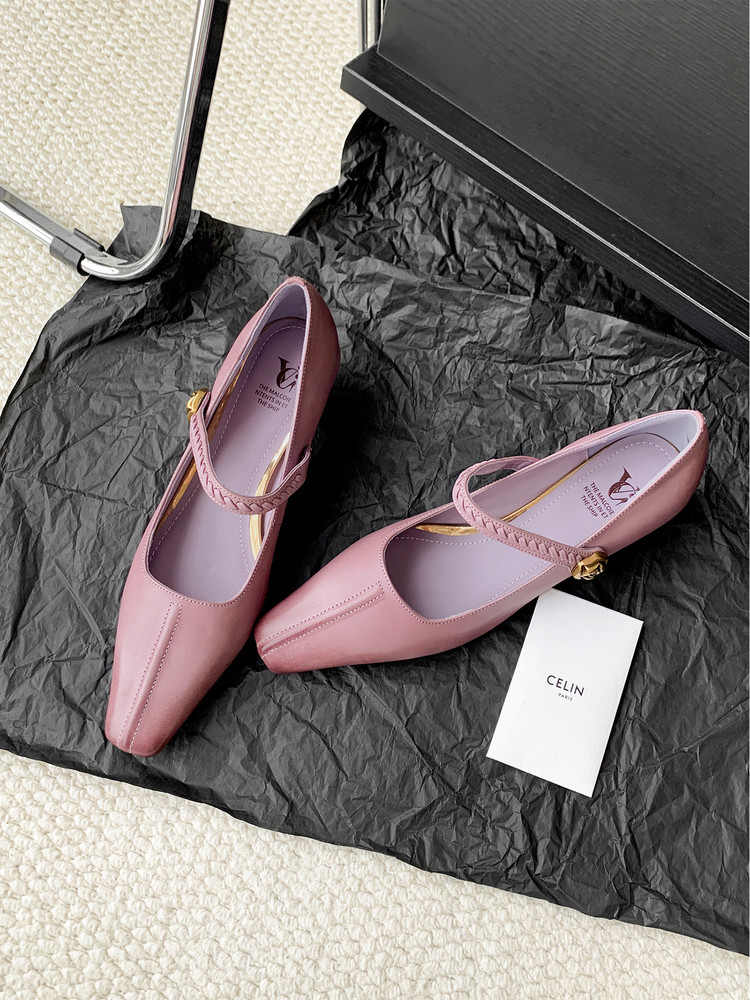 Pink pointed-toe Mary Jane flats photographed on black wrapping paper