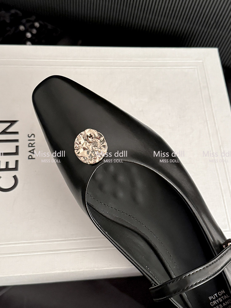 Black pointed-toe leather shoe with a gold decorative accent