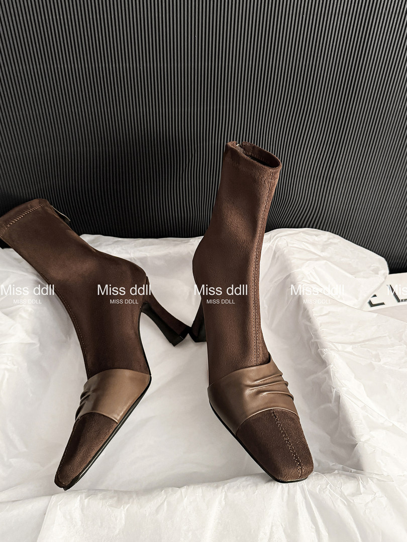 Brown heeled ankle boots displayed on white bedding