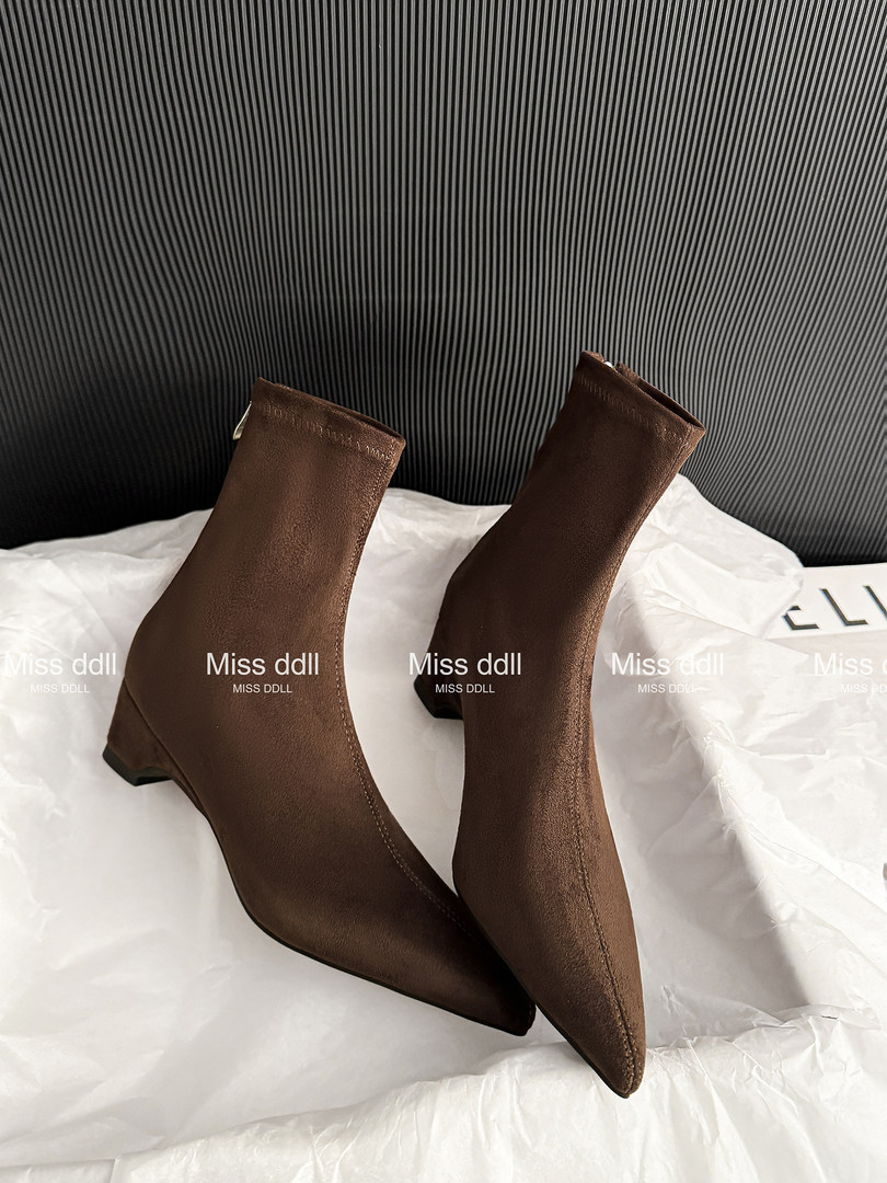Brown pointed-toe ankle boots photographed on white tissue paper