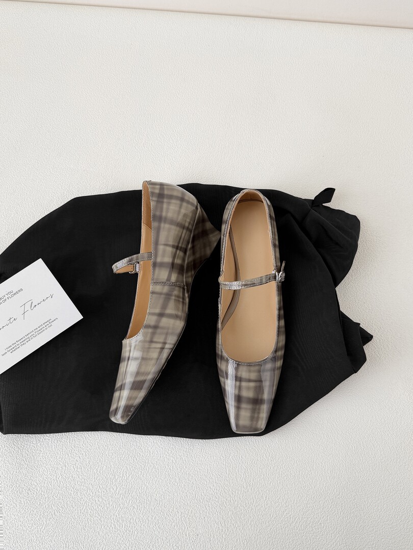 Pair of plaid pointed-toe Mary Jane flats laid on black fabric