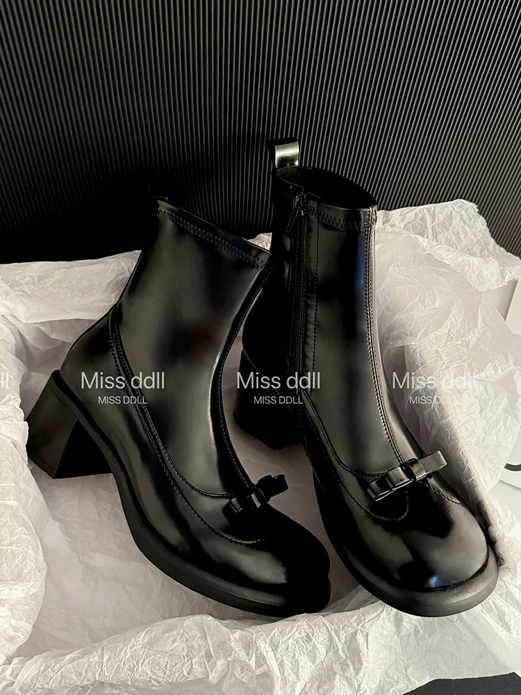 Black ankle boots with block heels and bow detail on tissue paper