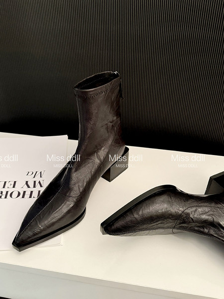 Black leather pointed-toe ankle boots with block heels displayed on a white surface