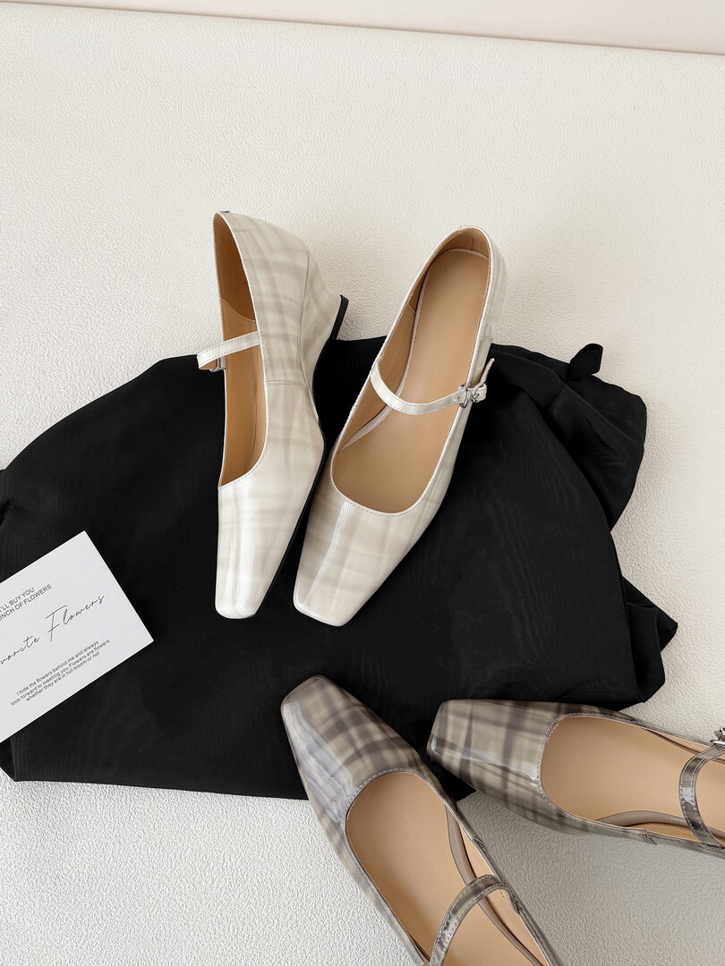 Pair of white plaid Mary Jane flats displayed on fabric