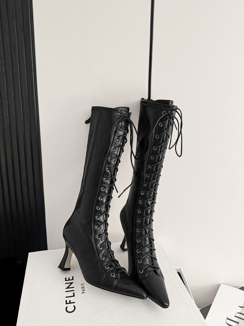 Black lace-up knee-high heeled boots on a white box
