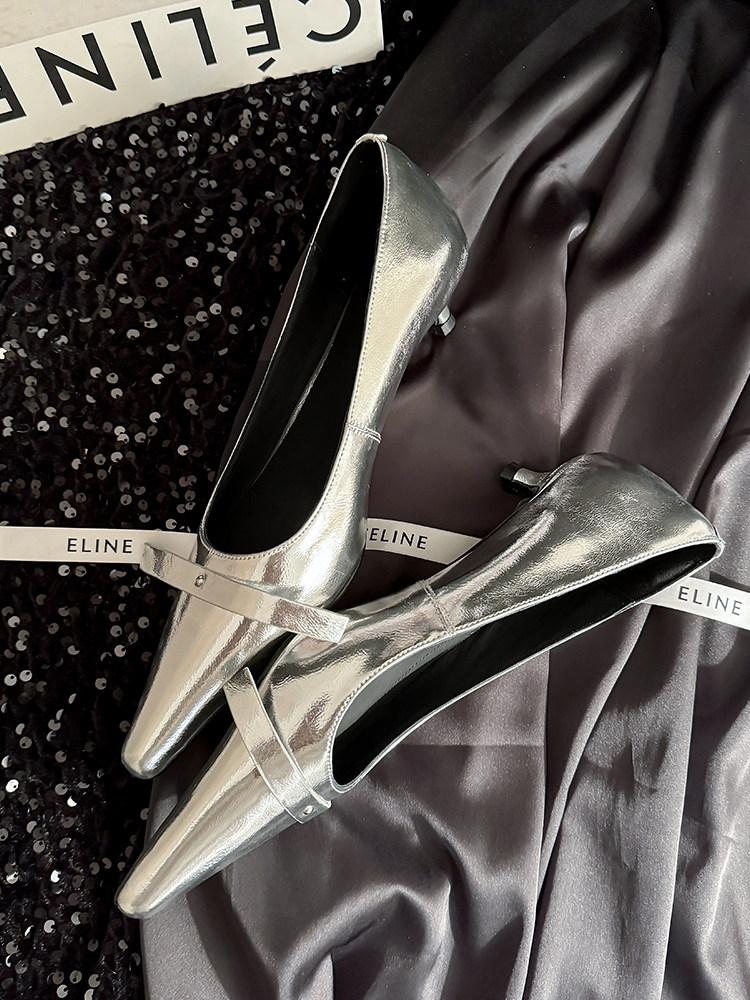 Silver pointed-toe high heels displayed on dark fabric
