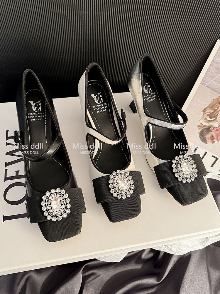 Black and silver embellished women's dress heels with jeweled buckles displayed on a box