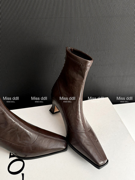 Brown leather pointed-toe heeled ankle boots on display