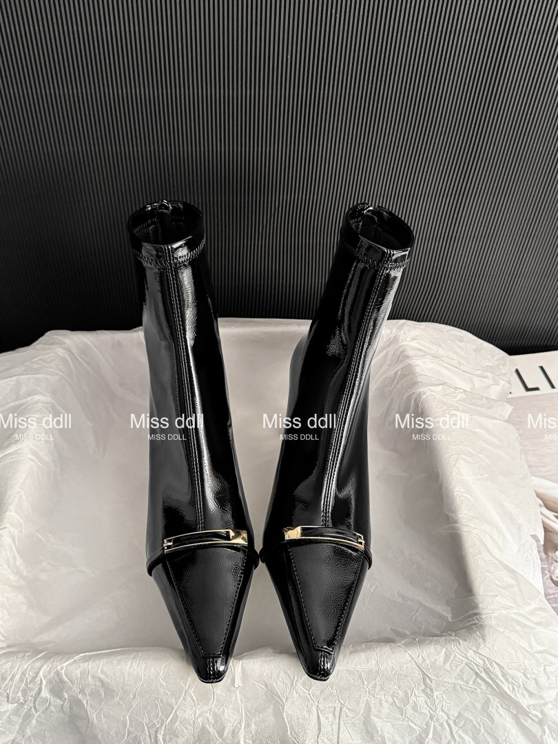 Pair of black glossy pointed-toe heeled boots displayed on a white surface