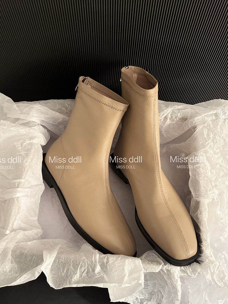 Pair of beige ankle boots displayed on tissue paper