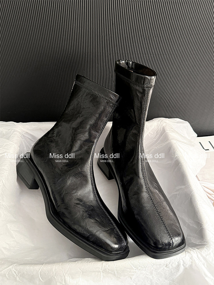 Black leather ankle boots with block heels displayed on a white surface