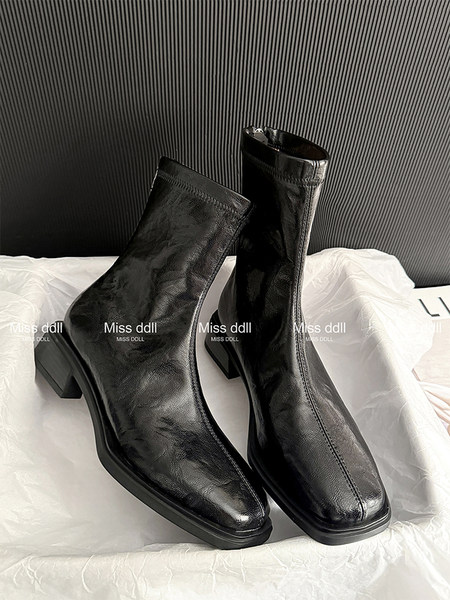 Black leather ankle boots with block heels displayed on a white surface