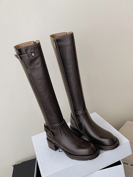 Pair of dark brown knee-high leather boots with chunky heels on a box