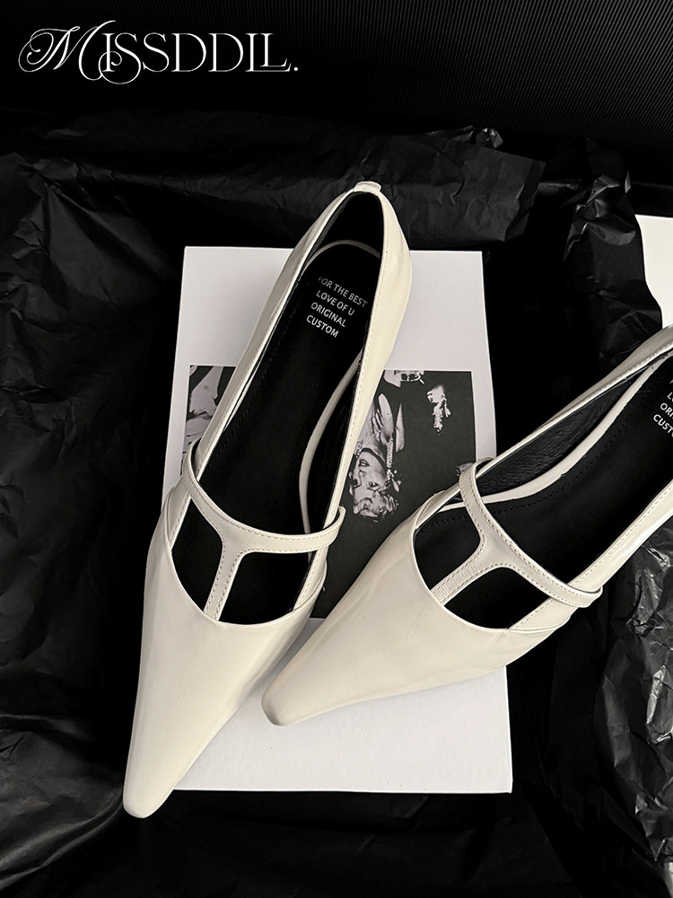 White pointed-toe shoes with strappy cutout design on a black background