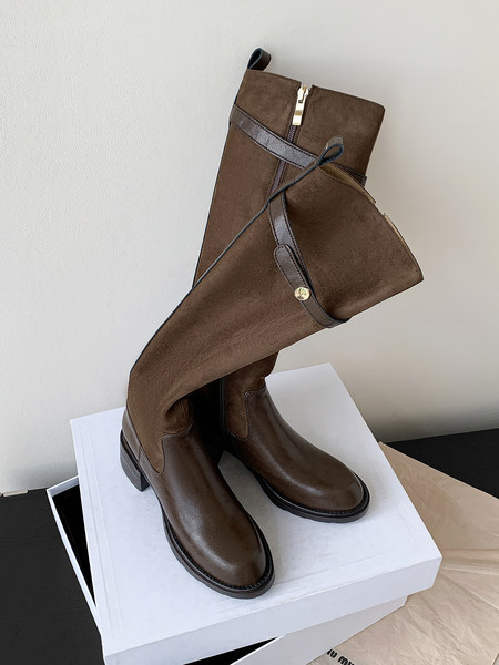 Brown knee-high leather boots displayed on a box