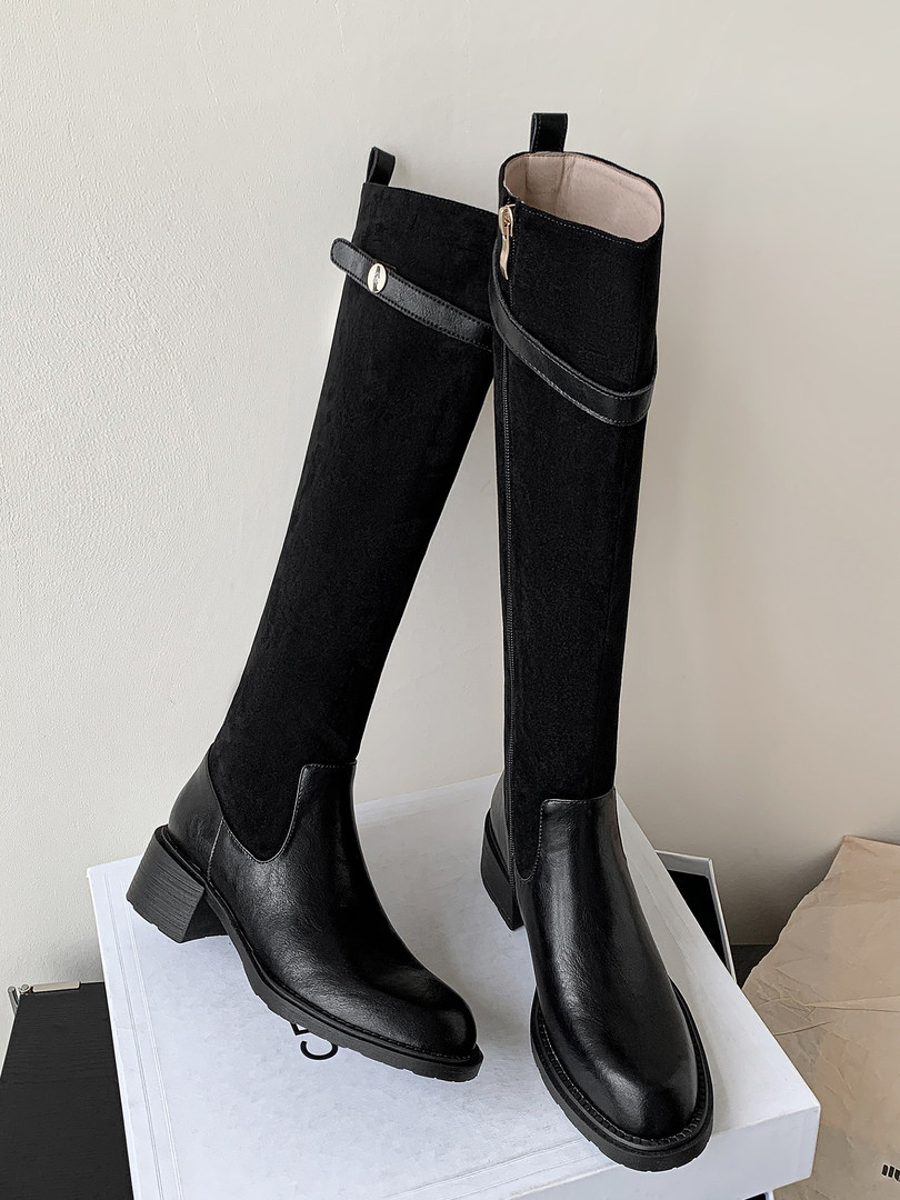 Black knee-high heeled boots displayed on a box