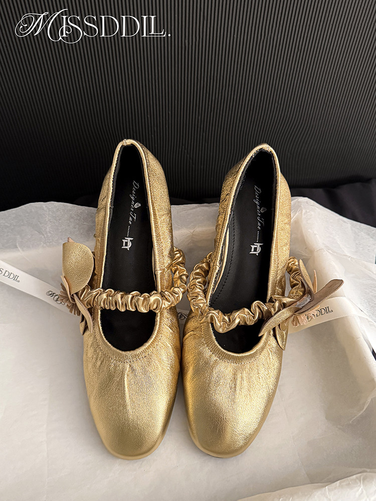 Pair of gold satin flat shoes with ruched straps