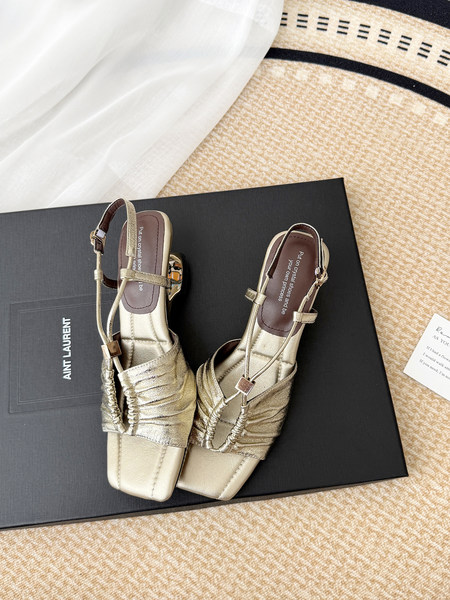 Pair of gold strappy heeled sandals on a black shoebox