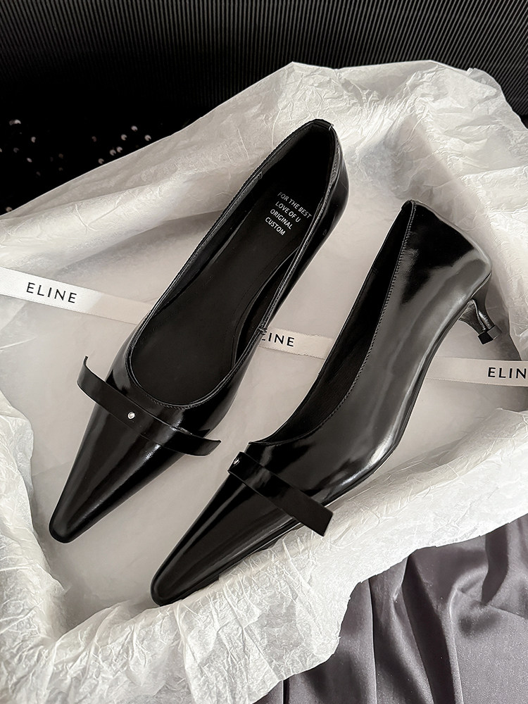 Black pointed-toe low heel shoes with a strap, displayed on tissue paper