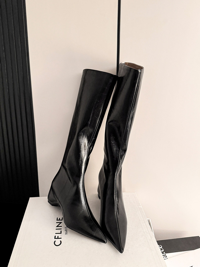 Black glossy knee-high pointed-toe boots displayed on a box