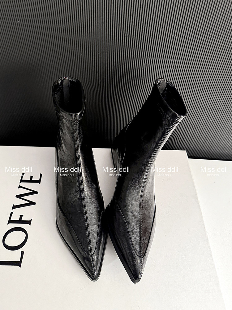 Black pointed-toe ankle boots on a white surface