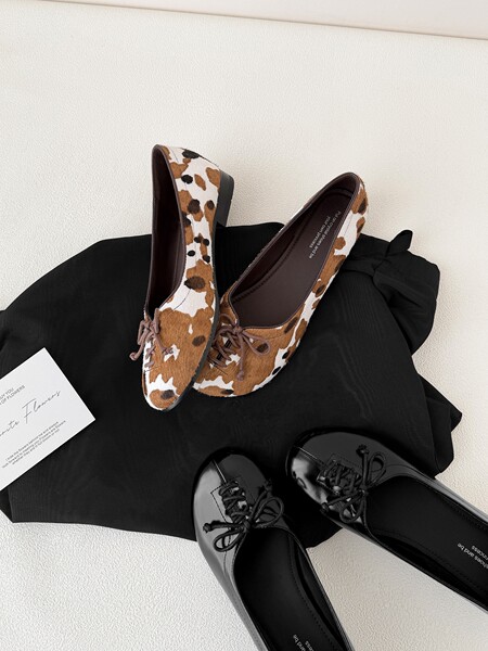 Animal-print and black lace-up flats displayed on black fabric