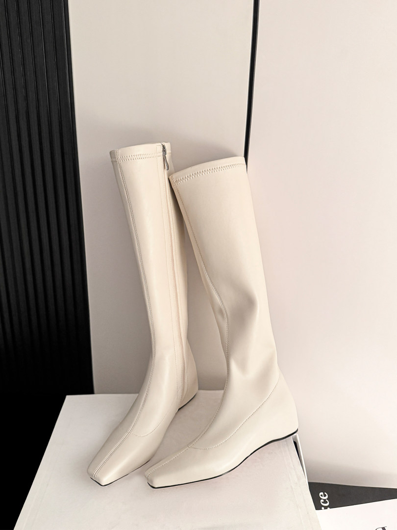 Pair of cream knee-high boots displayed on a surface