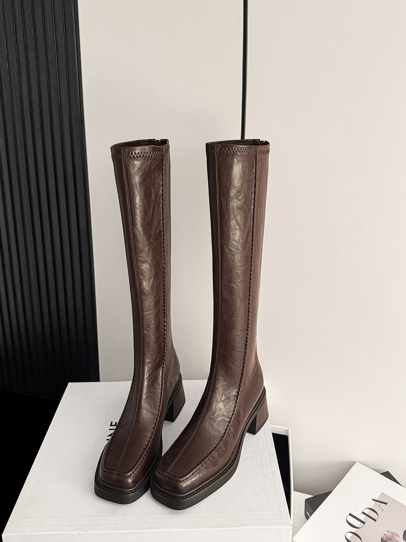 Pair of brown leather knee-high heeled boots on a display box