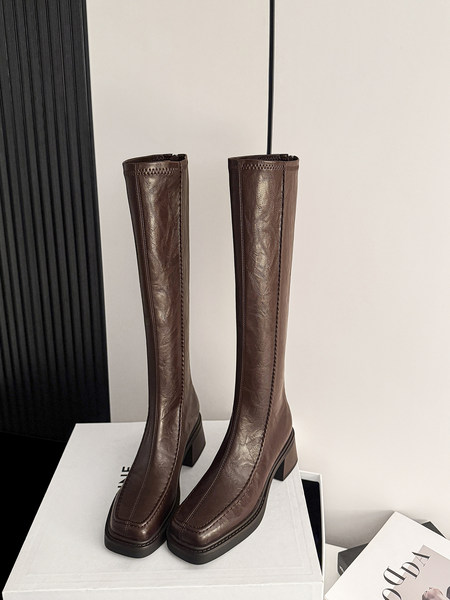 Pair of brown leather knee-high heeled boots on a display box