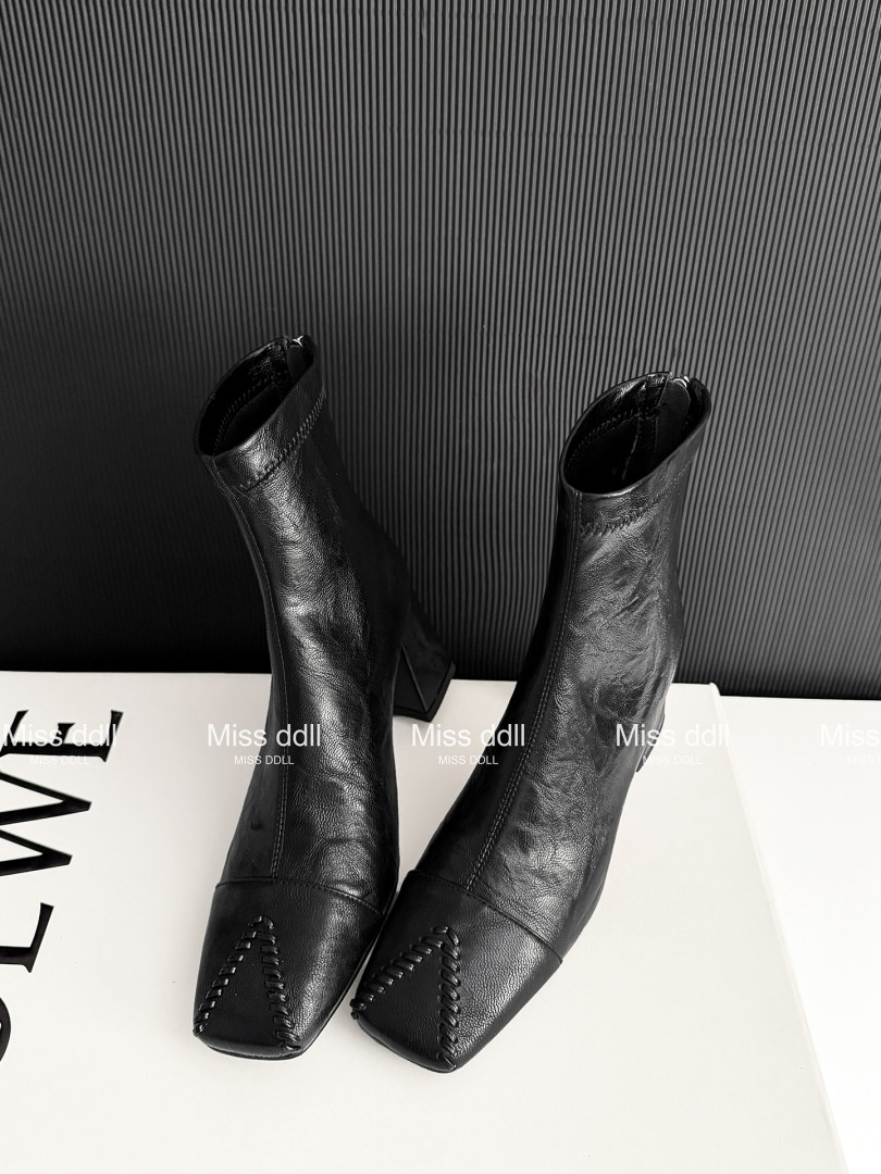 Black leather ankle boots displayed on a white surface