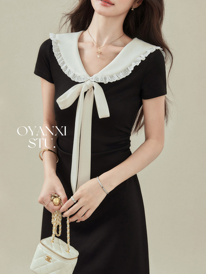 Black short-sleeve dress with a white sailor collar and bow, worn by a model
