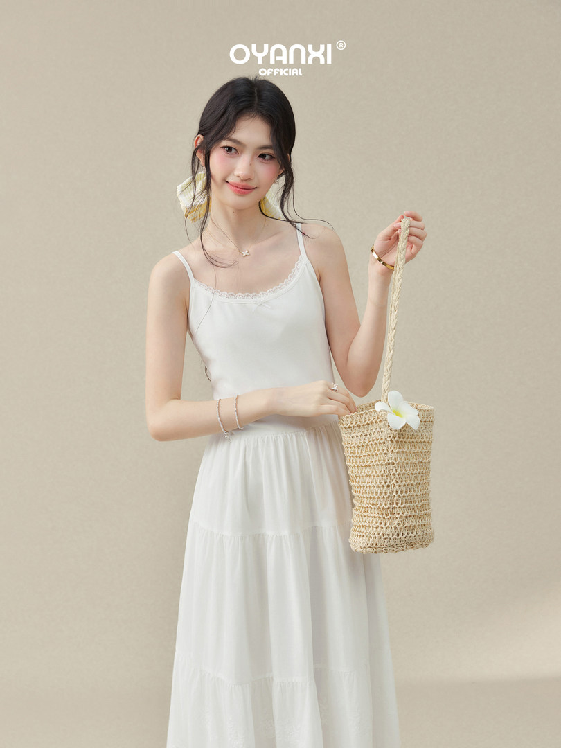 Woman wearing a white sleeveless summer dress with a woven straw bag