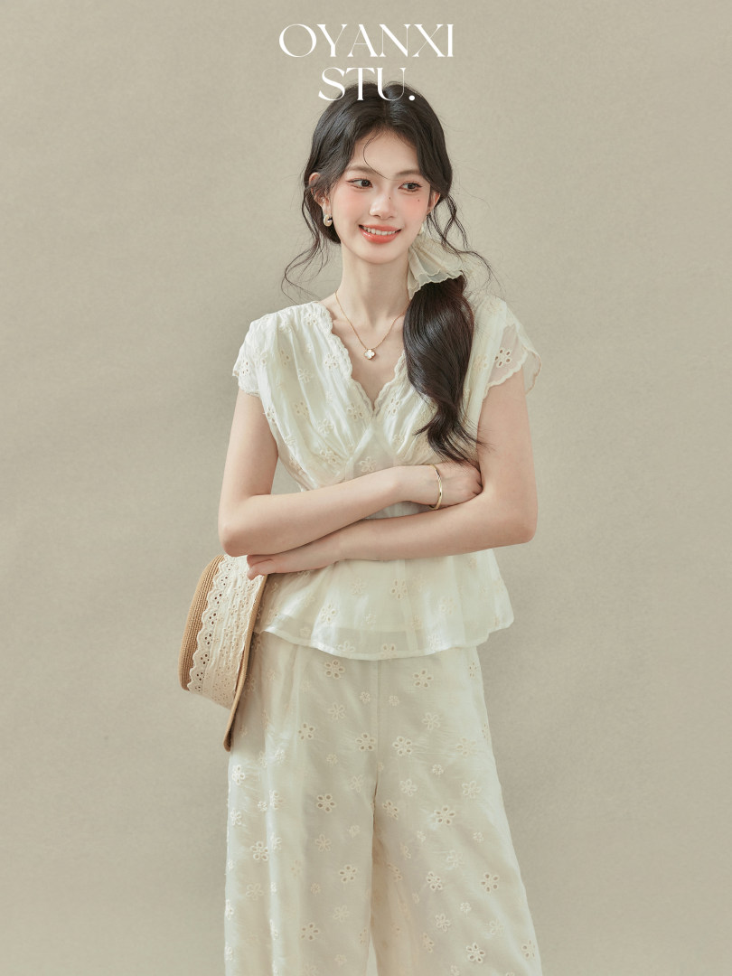 Model wearing a cream embroidered two-piece set with short sleeves and wide-leg pants