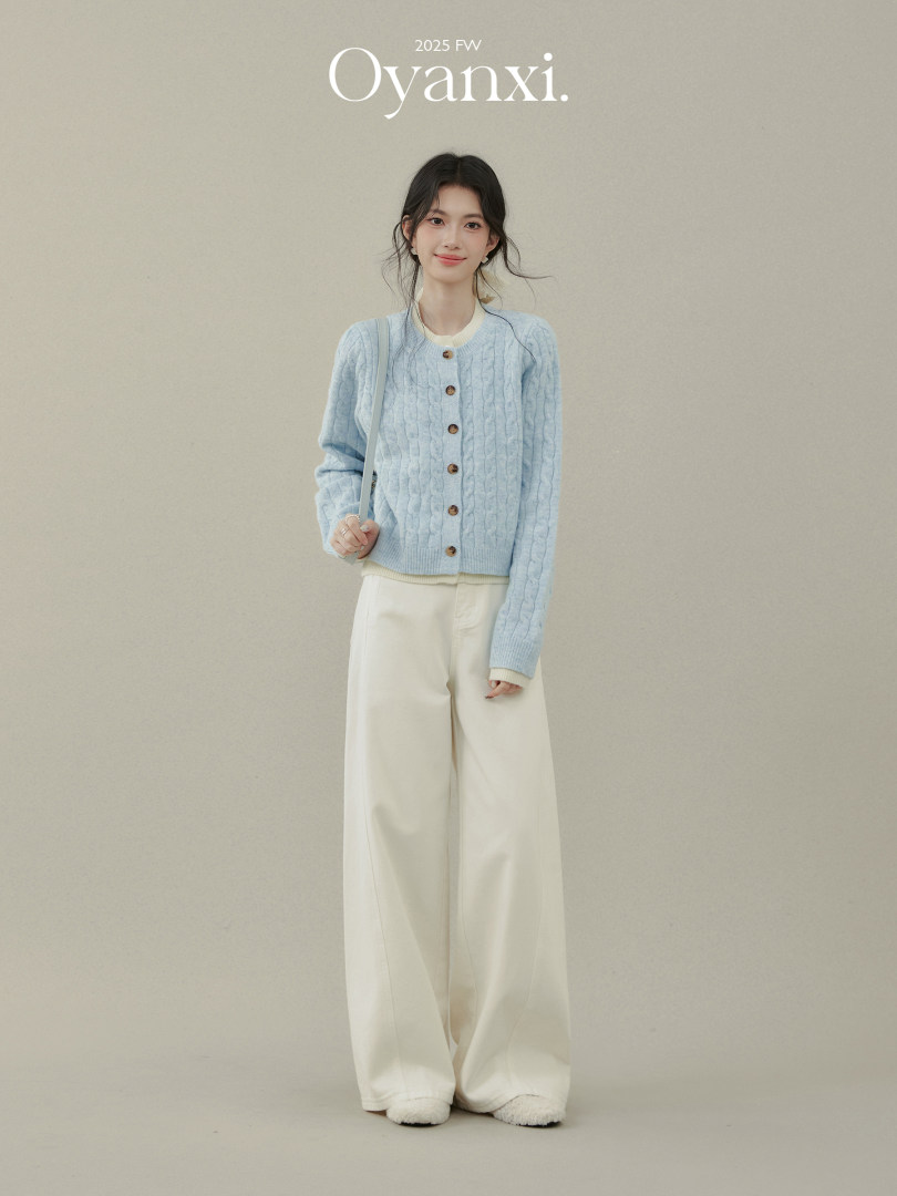 Model wearing a light blue cable-knit cardigan with cream wide-leg pants