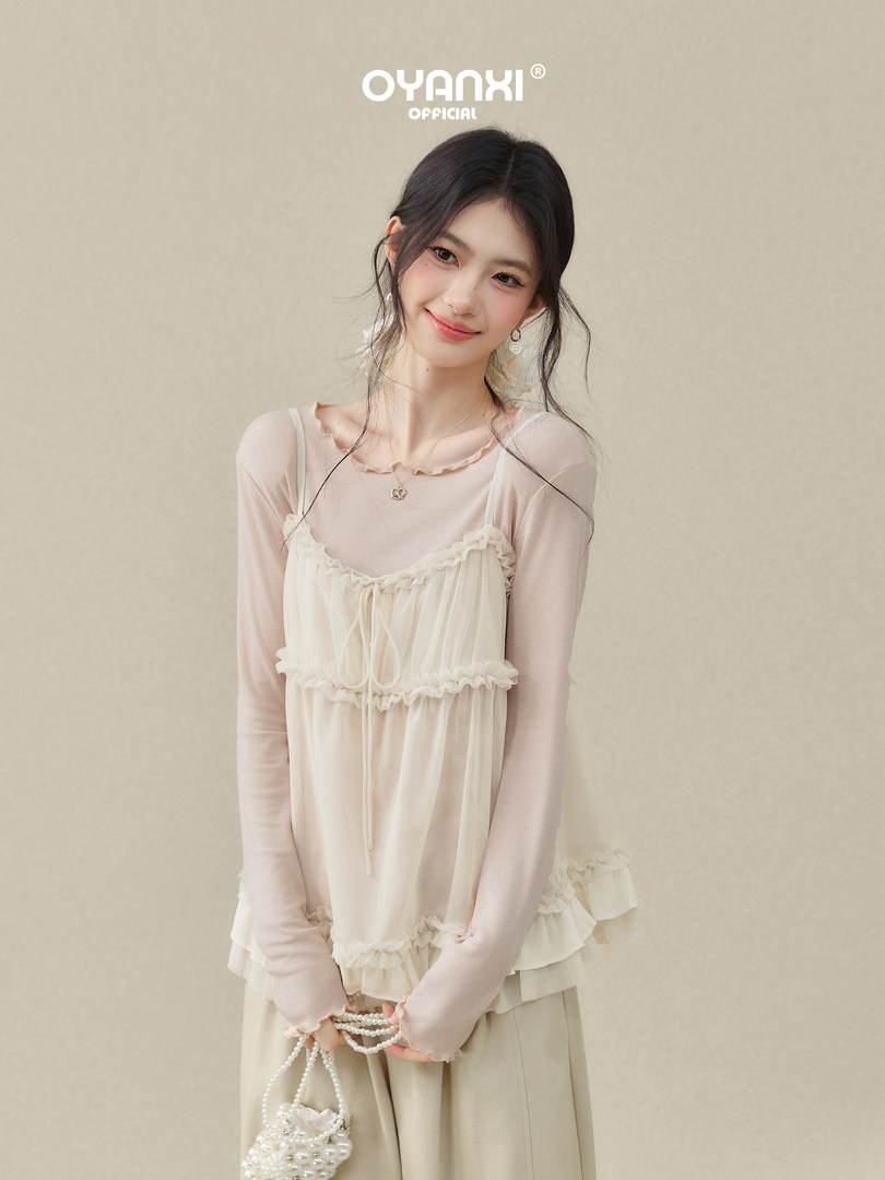 Model wearing a cream layered ruffle camisole with sheer long sleeves