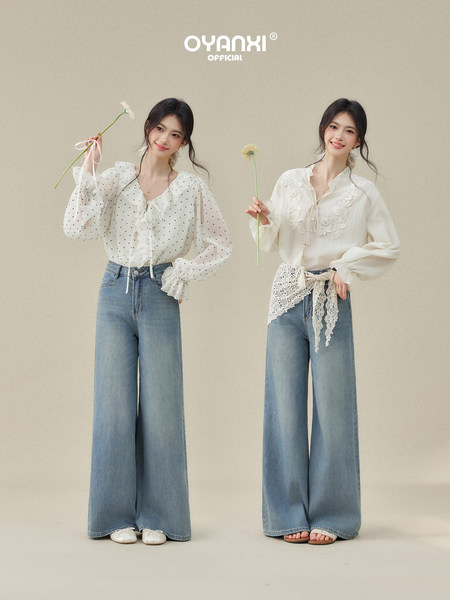 Two models wearing white blouses and wide-leg blue jeans.