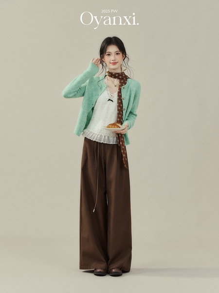 Model wearing a mint cardigan, lace top, brown wide-leg pants, and patterned scarf