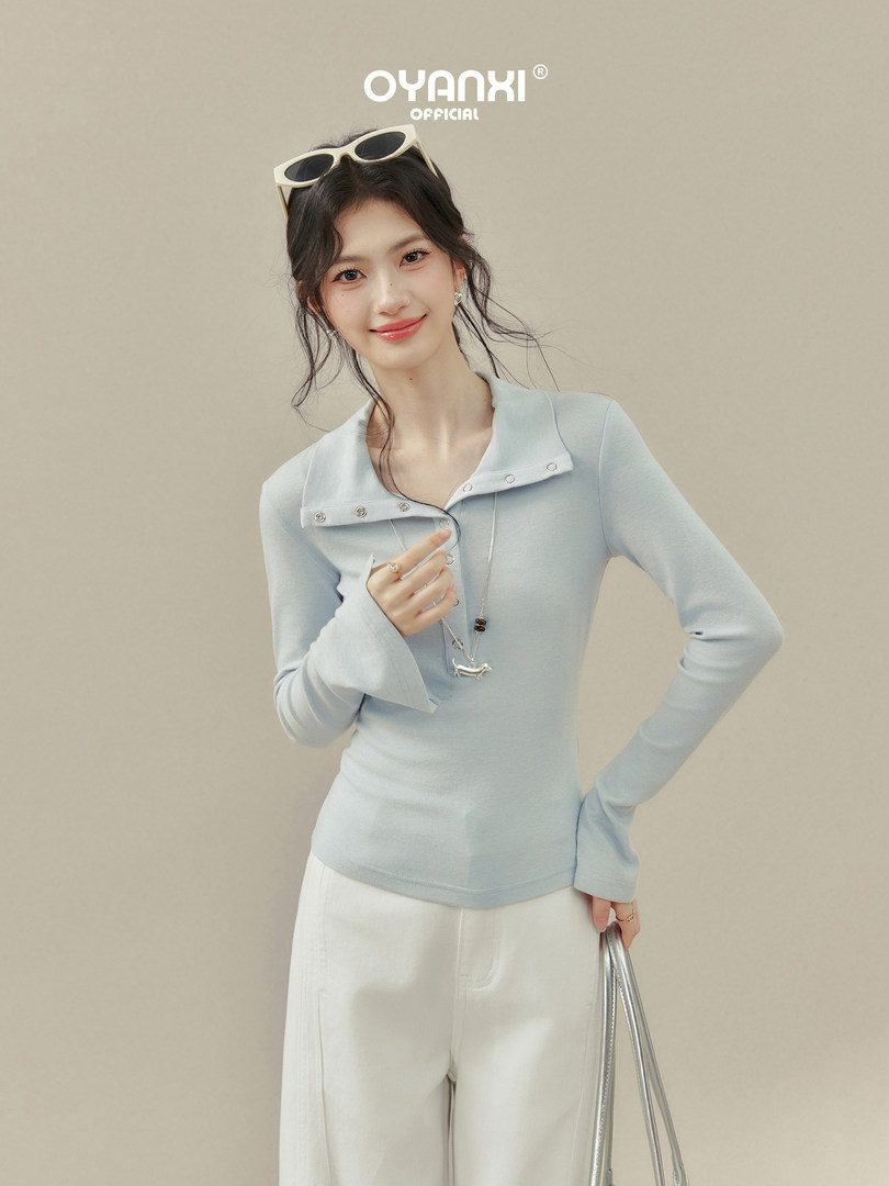 Model wearing a light blue long-sleeve fitted top with a wide collar
